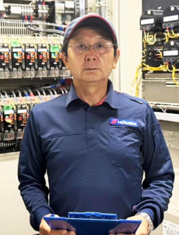 K.H.さんインタビューキービジュアル　配電盤設備を背景に立つポートレート